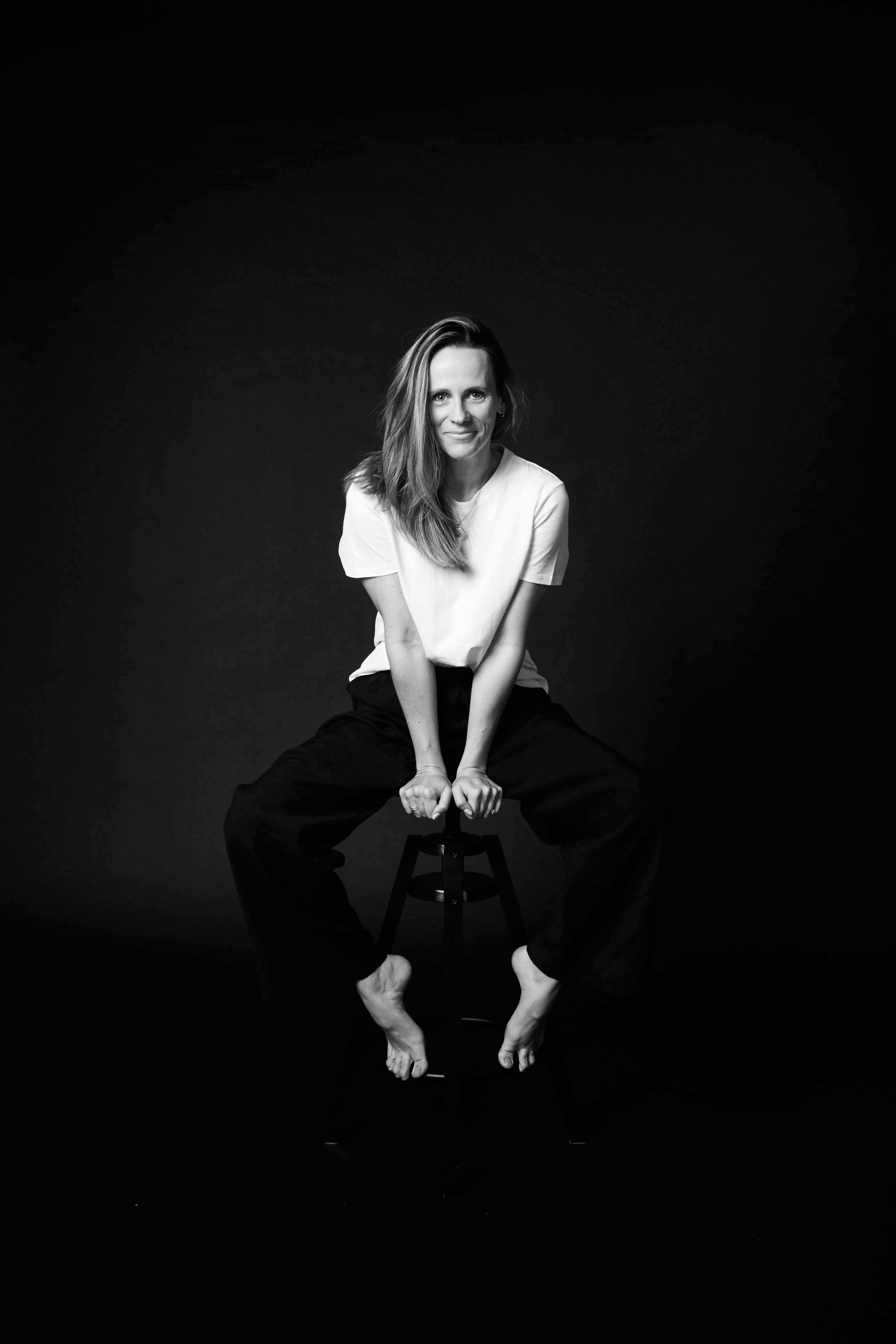 Chloe Cooper seated on a stool against black, looking straight to camera